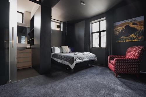 a bedroom with a bed and a red chair at New York Loft in Dunedin