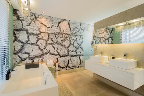 a bathroom with two sinks and a stone wall at The Olive Exclusive All-Suite Hotel in Windhoek
