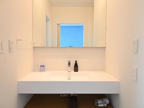 a bathroom with a white sink and a mirror at Solasuna in Yukuhashi