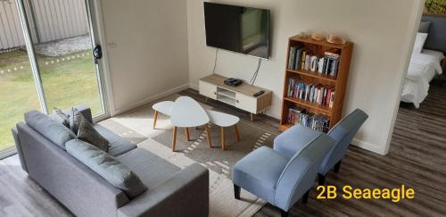 a living room with a couch and chairs and a tv at Dreamcatcher@Bicheno in Bicheno