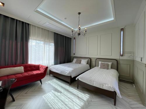 a bedroom with two beds and a red couch at Jimi Stay in Jeju