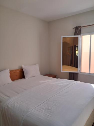 a bedroom with a large white bed and a mirror at Alshumukh guesthouse in Al Ghalīlah