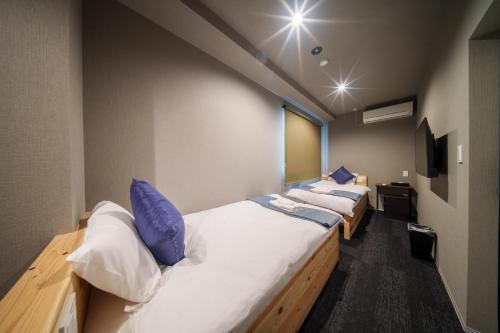 Pokój z 2 łóżkami i białymi i niebieskimi poduszkami w obiekcie BESTIE by DOYANEN w Osace