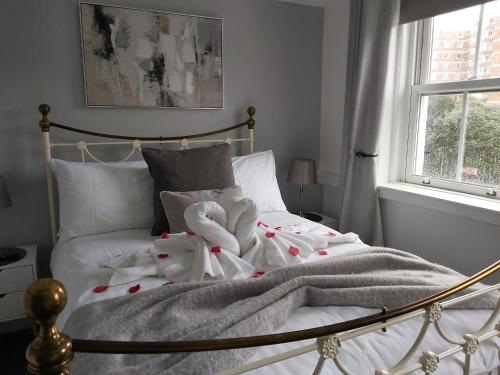 a white bed with two stuffed animals on it at #4 The Quirky Quarters in Portsmouth