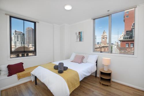 - une chambre blanche avec un lit et de grandes fenêtres dans l'établissement Vintage Charm 2 Bed Apt Near Flinders Station, à Melbourne