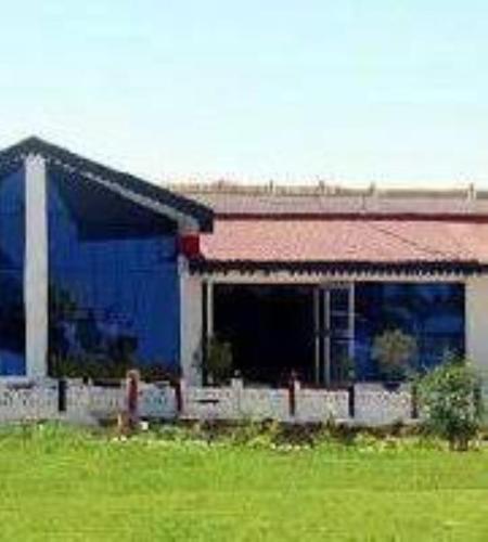 ein blaues Gebäude auf einem Feld neben einem Feld in der Unterkunft Hotel Sambodhi International, Madhya Pradesh in Sānchi