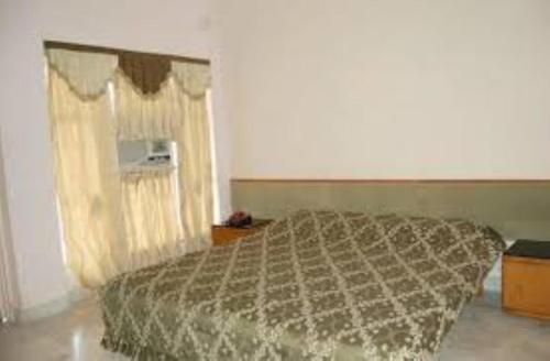 ein Schlafzimmer mit einem Bett mit einer Bettdecke in der Unterkunft Hotel Sambodhi International, Madhya Pradesh in Sānchi