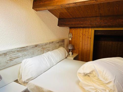 a bedroom with a white bed and a wooden wall at MIKKA FRONTERA DUPLEX PISTAS in Pas de la Casa