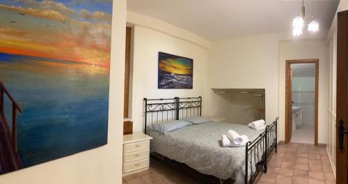 1 dormitorio con 1 cama y una pintura en la pared en Casetta Perseo, en Cammarata