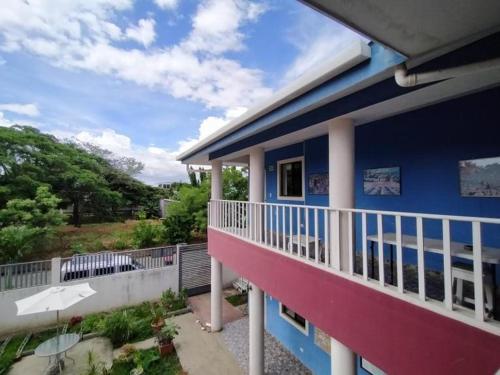 een blauw huis met een witte leuning op een balkon bij Montecristi Hotel Near the Nicaragua Intl Airport in Managua