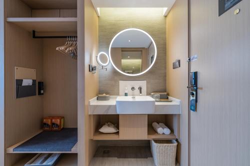 a bathroom with a sink and a mirror at Atour Hotel Hefei USTC Huangshan Road in Hefei