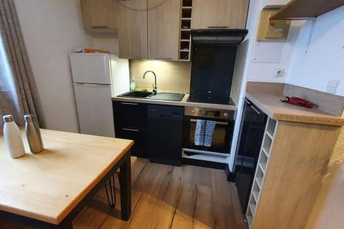 une cuisine avec des appareils noirs et une table en bois dans l'établissement Joli appartement 2min des pistes, avec 1 chambre et 1 coin montagne, à Vars