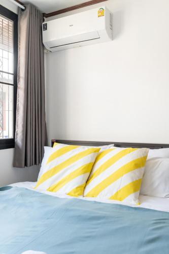 a bed with yellow and white pillows in a room at MIQ HK16, Huay Kwang MRT, 3BR, Pool Table in Ban Zong Katiam