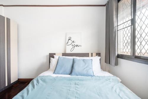 a bedroom with a bed with blue sheets and a window at MIQ HK16, Huay Kwang MRT, 3BR, Pool Table in Ban Zong Katiam