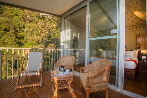 a screened in porch with two chairs and a bed at Yog Wellness Resort & Spa By Amritara in Mussoorie