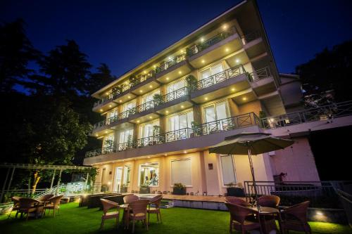a building with tables and chairs in front of it at night at Yog Wellness Resort & Spa By Amritara in Mussoorie
