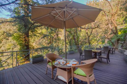 a table with an umbrella on a deck at Yog Wellness Resort & Spa By Amritara in Mussoorie