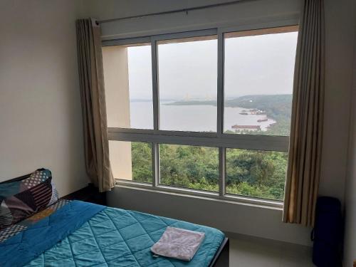 a bedroom with a large window with a view of a lake at Sea View with Balcony in Dabolim