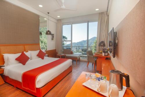a hotel room with a bed and a desk and a room with a view at Yog Wellness Resort & Spa By Amritara in Mussoorie