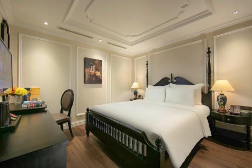 a bedroom with a large white bed and a desk at Amira Hotel Hanoi in Hanoi