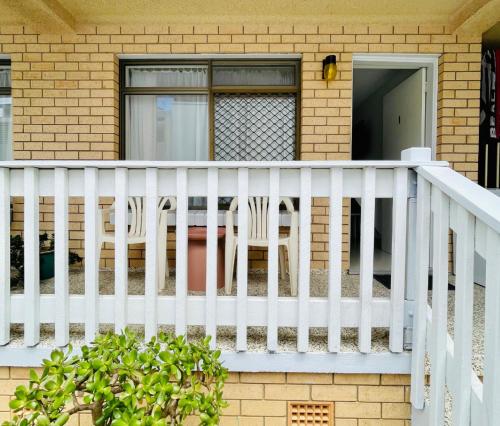 a porch with a white rail and chairs on a house at Bay Motel in Byron Bay