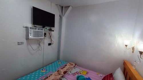 um pequeno quarto com uma cama e uma televisão em MJ Home em Manila