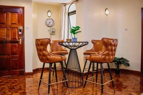 Habitación con 2 sillas, mesa y reloj en The happy place - Westlands, Nairobi en Nairobi