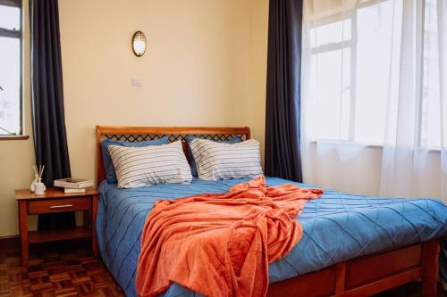 a bed with an orange blanket on it in a bedroom at The happy place - Westlands, Nairobi in Nairobi