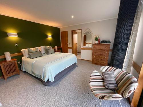 a bedroom with a large bed and a chair at Tikitere Lodge, Rotorua in Rotorua