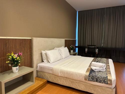 um quarto com uma cama e uma mesa com flores em The Platinum Kuala Lumpur by Aurora em Kuala Lumpur