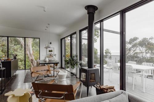 a living room with a fireplace and a table and chairs at Months and Seasons - Momentary Escapes - Coastal House in Wye River