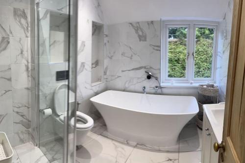 ein weißes Bad mit einer Badewanne und einem WC in der Unterkunft sandown cottage in esher in Esher