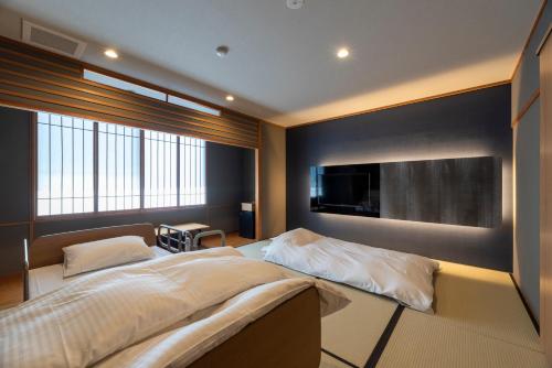 a bedroom with a large bed and a flat screen tv at サポートイン南知多 in Utsumi