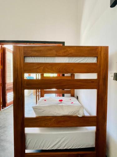 a bunk bed with white sheets and red flowers on it at Baobab Bungalows in Jambiani