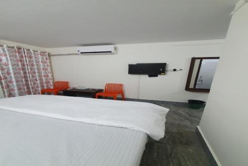 a bedroom with a bed and two chairs and a television at Hotel YLS, Itnagar in Itānagar