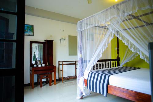 a bedroom with a canopy bed and a desk at Isindu Sky Lodge in Mirissa