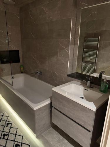 a bathroom with a white tub and a sink at Bedroom 2 in Elegant 3 Bed Flat in Ramsgate in Kent
