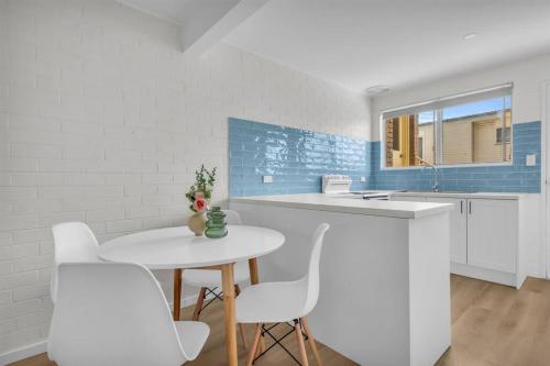 a kitchen with a white table and white chairs at Marine Court - Unit 6 in Merimbula