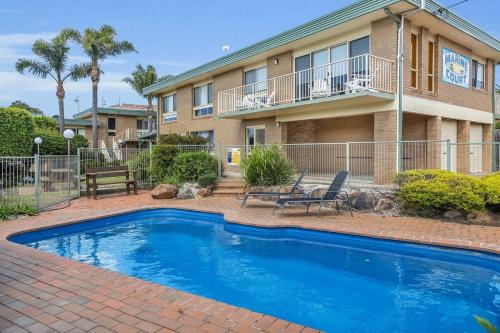 a swimming pool in front of a building with a house at Marine Court - Unit 6 in Merimbula