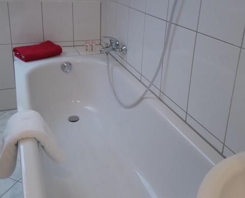 uma banheira branca na casa de banho com uma toalha vermelha em Ferienwohnung mit 2 Schlafzimmern und Parkplatz em Erfurt