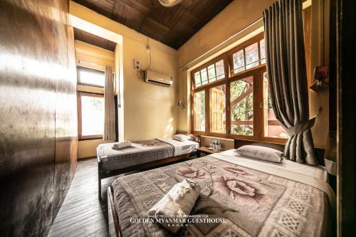 two beds in a room with two windows at Golden Myanmar Guest House in Bagan