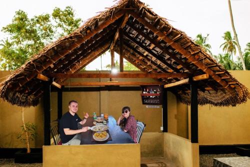 Ein Mann und eine Frau sitzen an einem Tisch mit Essen in der Unterkunft Villa Andaz in Negombo