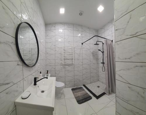 a white bathroom with a sink and a mirror at Apartamentai Harmonija in Akmenė