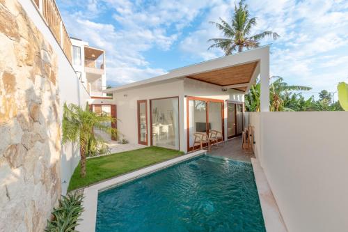 a villa with a swimming pool in front of a house at Pagi Villas by Hombali in Mengwi