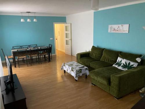 ein Wohnzimmer mit einem grünen Sofa und einem Tisch in der Unterkunft Para amantes de espacios amplios, sol y relax in Argentona