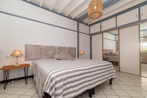 ein Schlafzimmer mit einem großen Bett und einer gestreiften Decke in der Unterkunft Villa 400m2, 10 pers St Clotilde in Saint-Denis