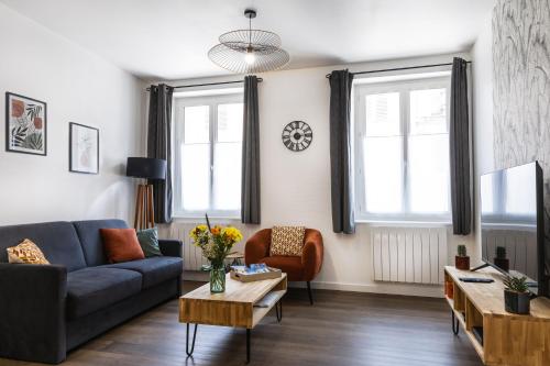 een woonkamer met een bank en een tafel bij Le Constantin - Ecrin chaleureux & confortable, centre-ville à 2 pas in Provins