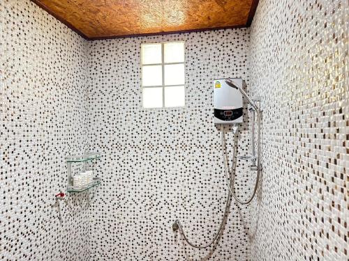 a white tiled bathroom with a shower with a window at บ้านสวนปิยนันท์ (Baansuan Piyanan) in Ko Yao Noi