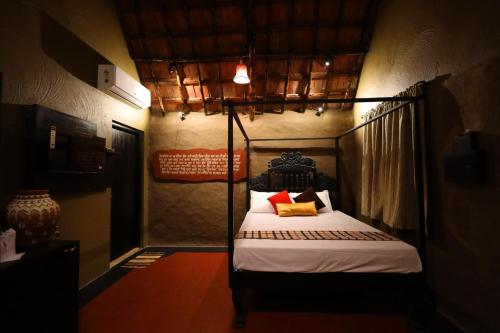 a bedroom with a four poster bed in a room at Arshinagar Shilpogram in Kolkata