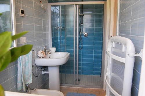 een badkamer met een wastafel en een douche met blauwe tegels bij Lovely apartment close to Bibione beach in Bibione